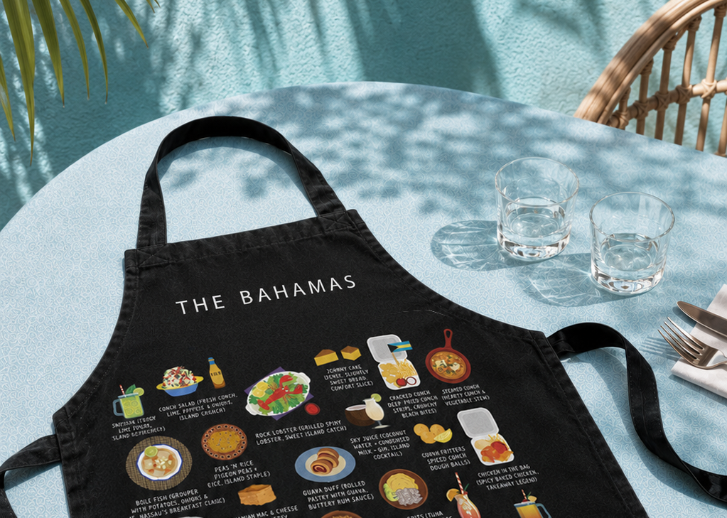 Maison Maps Bahamas apron styled on a poolside table with palm shadows and glassware